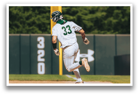 A baseball player in a black shirt and black socks is bending over to catch a ball. Description generated by AI