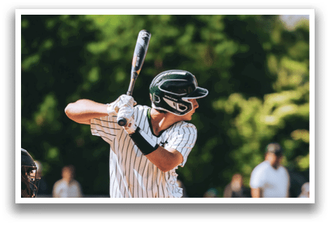 A baseball player in a black shirt and black socks is bending over to catch a ball. Description generated by AI