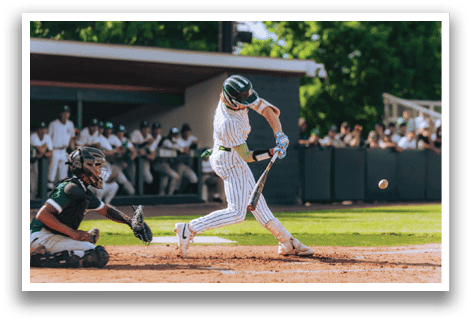 A baseball player in a black shirt and black socks is bending over to catch a ball. Description generated by AI