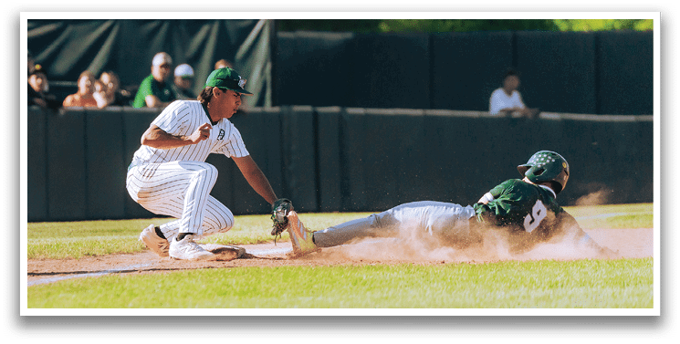 A baseball game is taking place with a man in a black shirt and gray pants standing behind a catcher. Description generated by AI