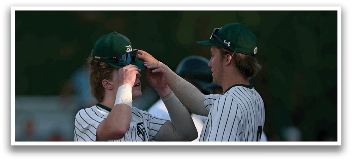 A man and woman are standing on a field with a football player in a green and white uniform. Description generated by AI