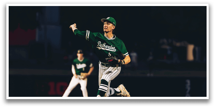 A baseball game is taking place with a man in a black shirt and gray pants standing behind a catcher. Description generated by AI