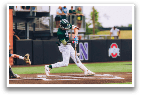 A baseball player in a black shirt and black socks is bending over to catch a ball. Description generated by AI
