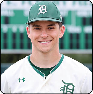 A baseball player wearing a green and white uniform with the number 14 on the back. Description generated by AI