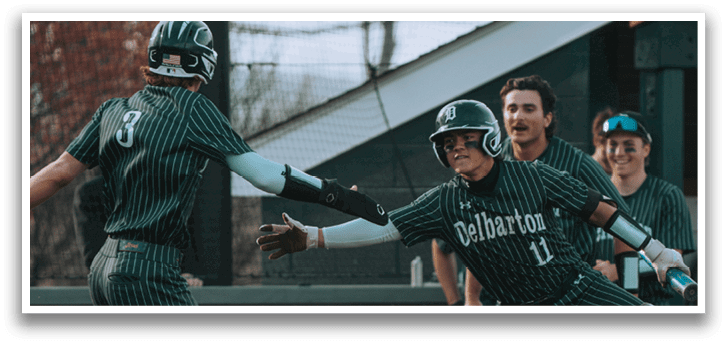 A baseball player in a green and white uniform is squatting on the ground. Description generated by AI