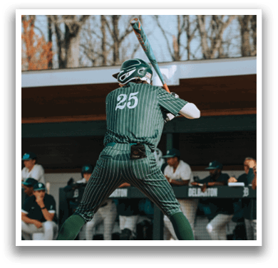 A baseball player in a green and white uniform is swinging a bat. Description generated by AI
