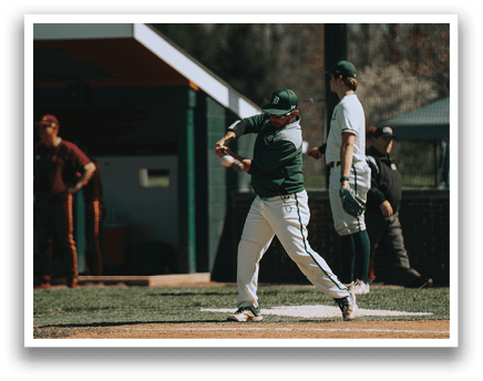 A baseball player in a green shirt and white pants is swinging a bat. Description generated by AI