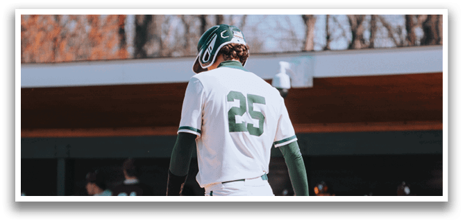 A baseball player wearing a green and white uniform is walking away from home plate. Description generated by AI