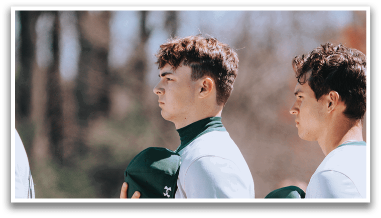 Two baseball players wearing green and white uniforms. Description generated by AI