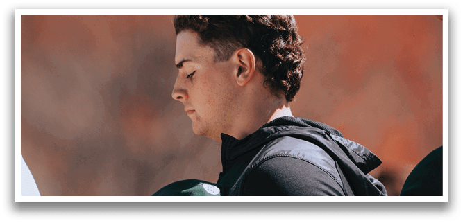 A man wearing a black jacket and a green hat. Description generated by AI