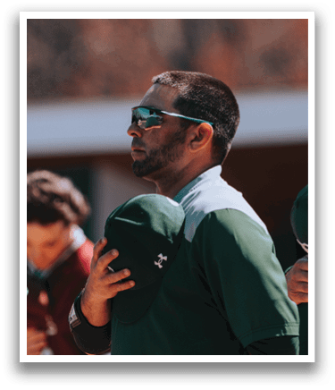 A man wearing a green and white shirt and sunglasses. Description generated by AI