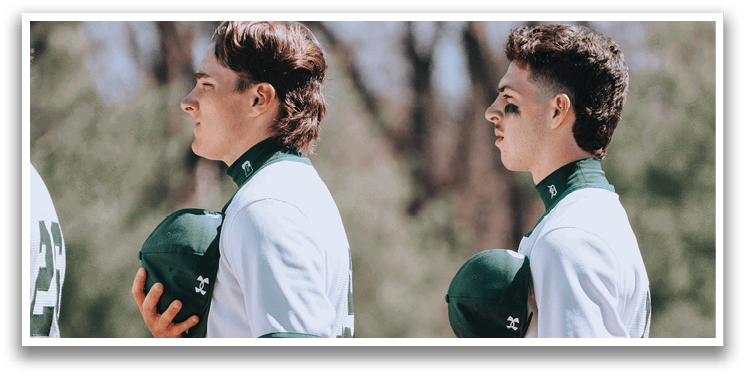Two baseball players wearing green and white uniforms. Description generated by AI