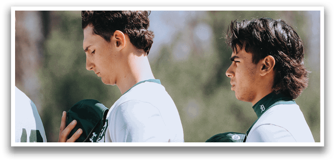 Two baseball players wearing green and white uniforms. Description generated by AI