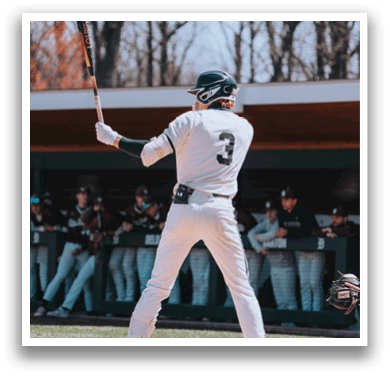 A baseball player in a white uniform is holding a bat and getting ready to swing. Description generated by AI