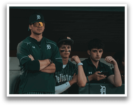 A baseball player in a black and green striped uniform is pitching a ball. Description generated by AI