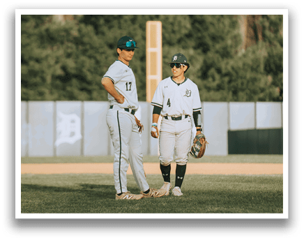 Two baseball players standing on a field. Description generated by AI