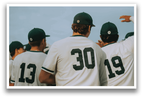 A group of baseball players wearing green and white uniforms. Description generated by AI