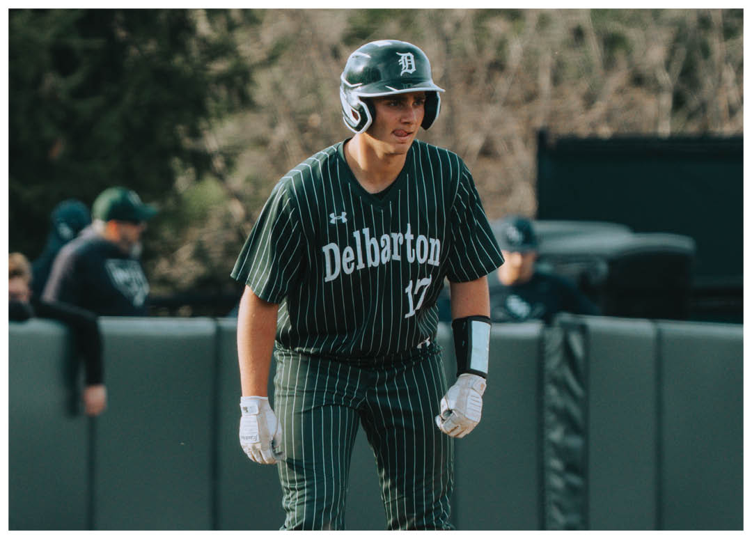 A baseball player wearing a green and white uniform is in the process of throwing a ball. Description generated by AI