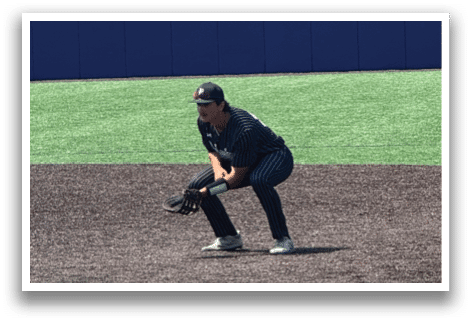 A baseball player is crouching on the field. Description generated by AI