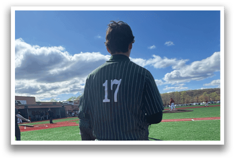 A baseball player wearing a green and white uniform. Description generated by AI