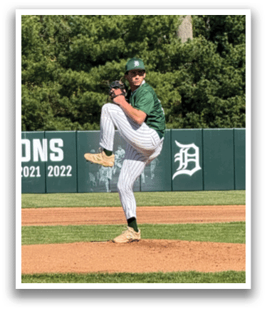 A baseball player in a green shirt and white pants is pitching a ball. Description generated by AI