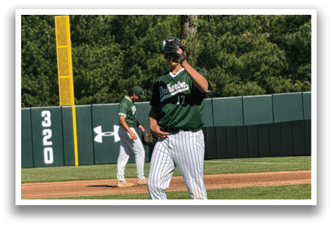 A baseball player wearing a green shirt and white pants. Description generated by AI