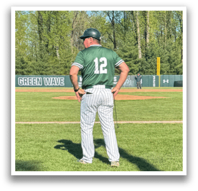 A baseball coach standing on the field. Description generated by AI