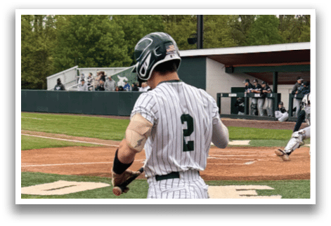 A baseball player is holding a bat and standing on the field. Description generated by AI