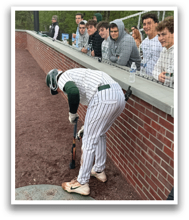 A baseball player bending over to touch a bat. Description generated by AI