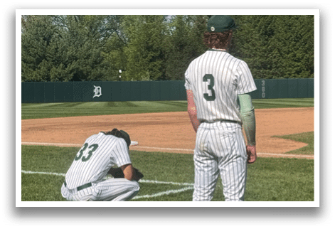 A man standing on a baseball field. Description generated by AI