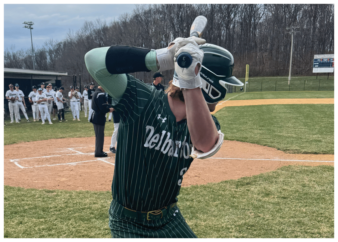A baseball player in a green and white uniform is swinging a bat. Description generated by AI