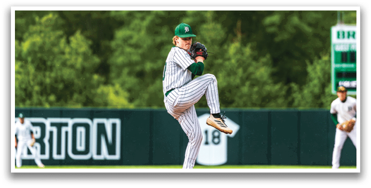 A baseball player in a green hat and striped shirt is pitching a ball. Description generated by AI