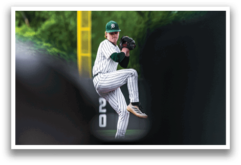 A baseball player in a green and white uniform is throwing a ball. Description generated by AI