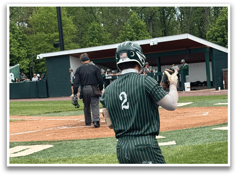 A baseball player wearing a green and white uniform is running to first base. Description generated by AI