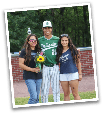 A man and two women are standing in front of a baseball field. Description generated by AI