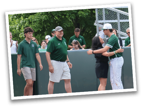 A man and woman hugging on a baseball field. Description generated by AI