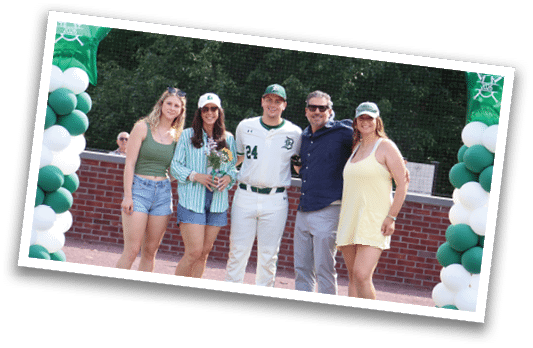 A group of people standing in front of a baseball field. Description generated by AI