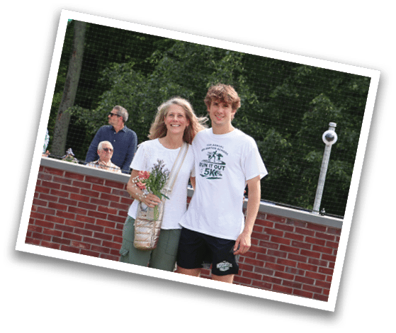 A man and woman standing in front of a red brick wall. Description generated by AI