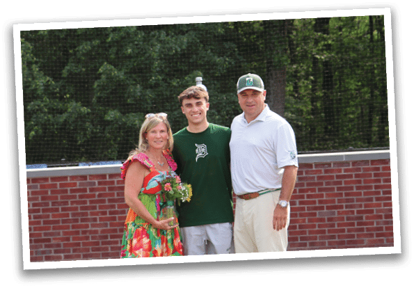 A man, woman, and boy are standing in front of a brick wall. Description generated by AI