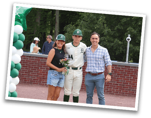 A man, woman, and boy stand in front of a banner. Description generated by AI