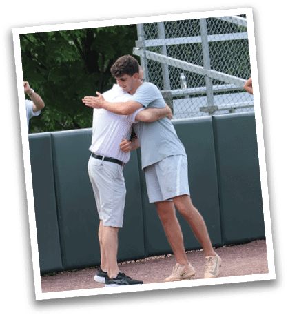 Two men hugging on a baseball field. Description generated by AI