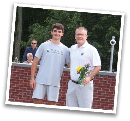 Two men standing in front of a brick wall. Description generated by AI