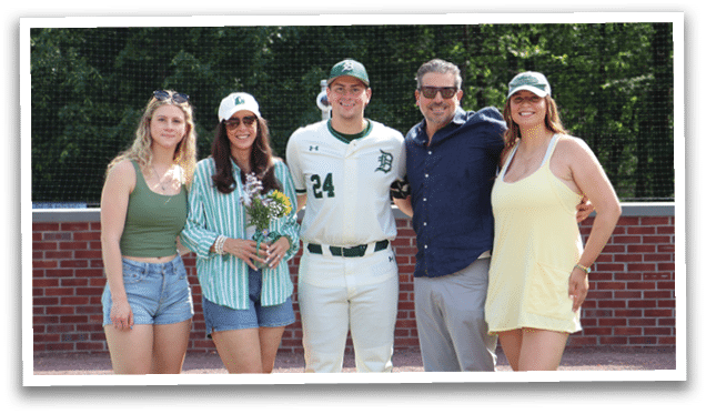 A group of people standing in front of a baseball field. Description generated by AI