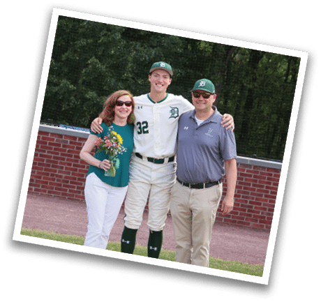 A man and woman standing in front of a baseball field. Description generated by AI