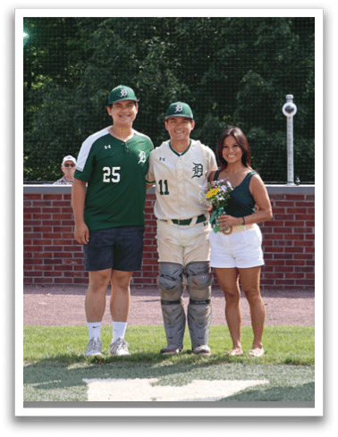 A man and woman standing in front of a baseball field. Description generated by AI