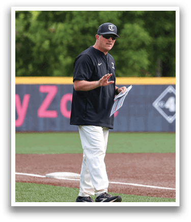 A man wearing a black shirt and white pants is standing on a baseball field, talking on a cell phone. AI generated content