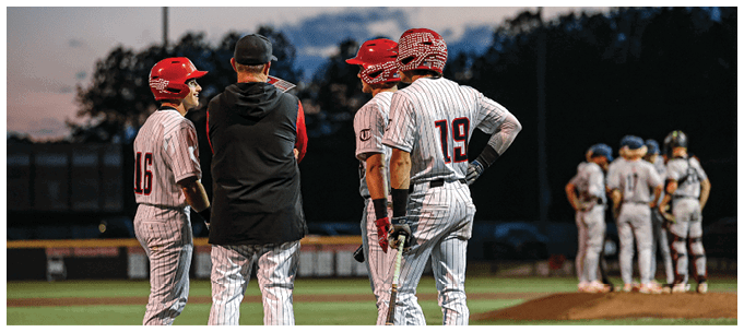 A group of baseball players standing on a field, with one player holding a bat. AI generated content