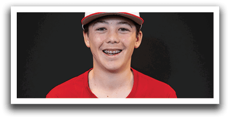 A young boy wearing a baseball uniform is sitting down. AI generated content