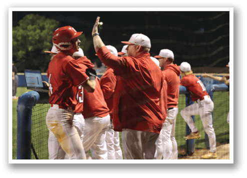 A group of baseball players huddle together on the field, with one man raising his hand in the air. AI generated content