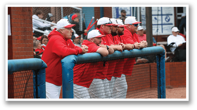 A group of men wearing red shirts and white hats are standing next to a fence. AI generated content